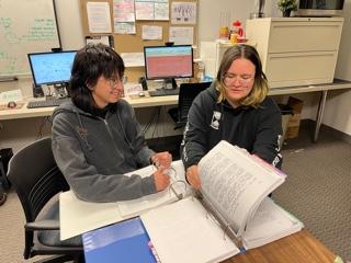 Two students reading a manuscript in a binder