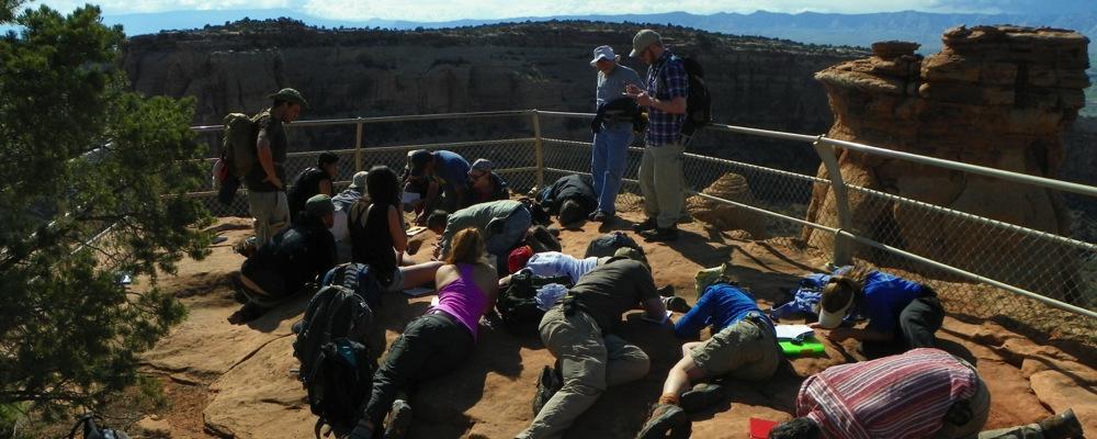 Geology students inspect the geology of the top of a cliff