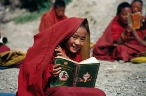 Picture of a smiling boy reading a buddhist text