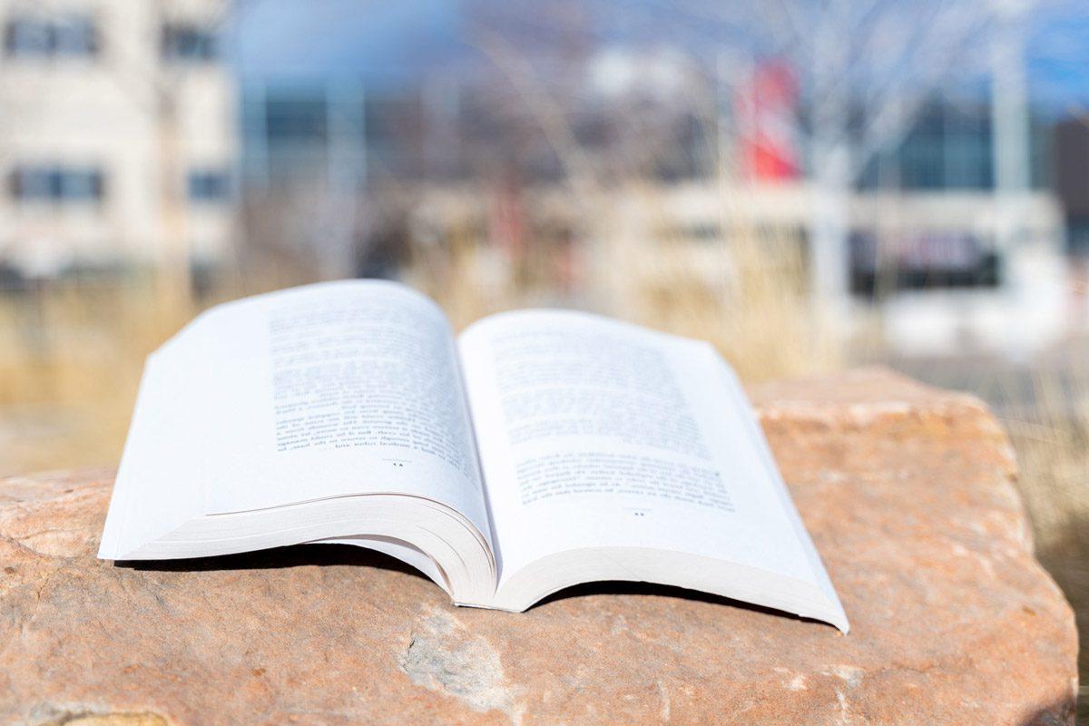 open book sitting on a rock on campus