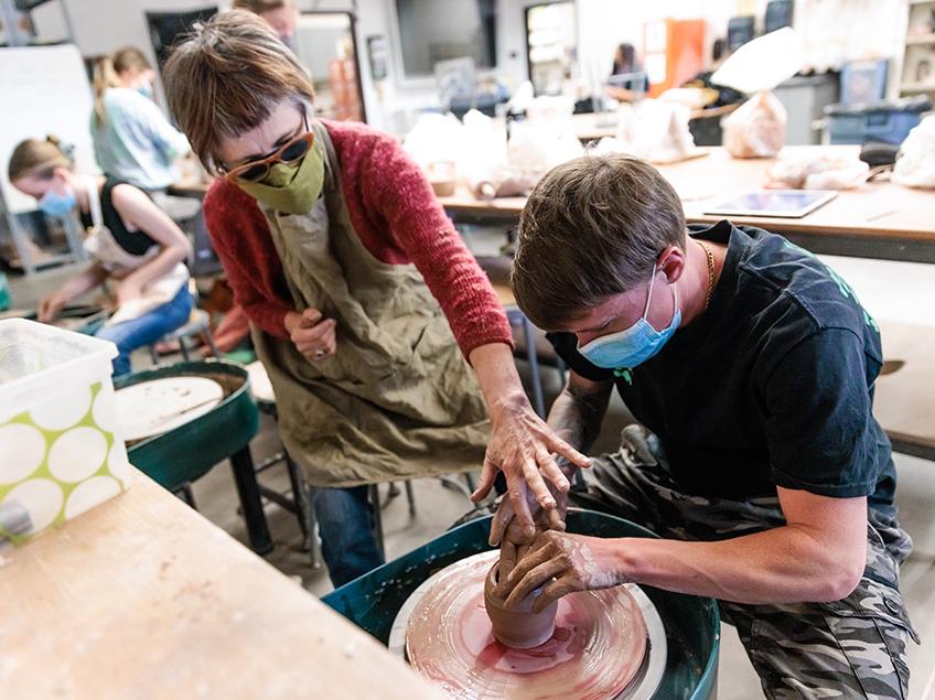 Professor Tsehai Johnson assists a student with their pottery-throwing exercise.